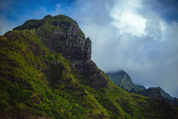 Fototapeta na wymiar The gorgeous rugged wilderness and cliffs of Kauai's Napali Coast in Hawaii, with low clouds and mist hanging over the mountain peaks under a stormy grey sky