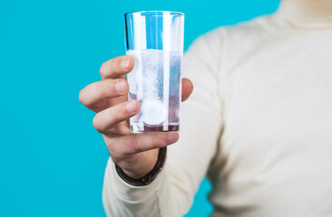 White pill and a glass of water in man hands. Health concept. Close up of man holding a pill. Glass of water tablet. Glass with efervescent tablet in water with bubbles