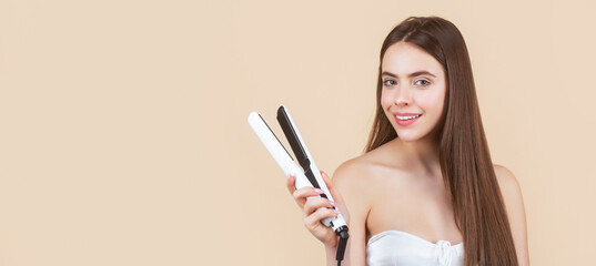 Hairstyle. Beautiful smiling woman ironing long hair with flat iron. Woman straightening hair with straightener. Portrait of young beautiful girl using styler on her shining hair - obrazy, fototapety, plakaty