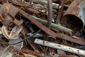 scrap metal, old rusty metal lying on green grass. Pipes, batteries, heating system is old outside