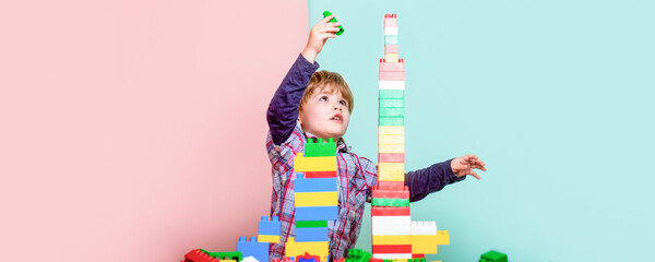 Boy playing with construction blocks at kindergarten. Child playing with colorful toy blocks. Educational toys for young children. Little boy playing with lots of colorful plastic blocks constructor