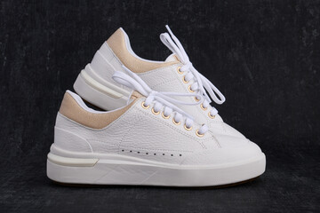 Light womens leather sneakers on a dark background close up