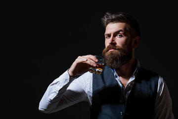 Bearded businessman in elegant suit with glass of whiskey. Degustation, tasting. Man with beard holds glass of brandy. Tasting and degustation concept