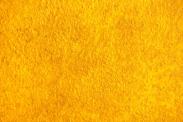 Golden wall with abstract spots as a background. Beautiful golden texture with patterns, decorative plaster. Modern bright wall painting in trendy shades, unusual spotted yellow and gold surface.