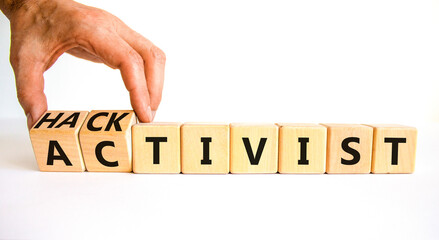 Activist or hacktivist symbol. Businessman turns wooden cubes and changes the word Activist to Hacktivist. Beautiful white table white background, copy space. Business activist or hacktivist concept.