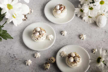 Culinary presentation of meringue dishes garnished with quail eggs, complemented by bright white daisies.