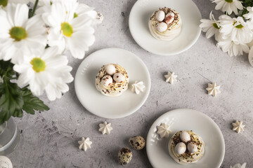 A showcase of meringue treats and quail eggs set against white daisies and a neutral gray backdrop.