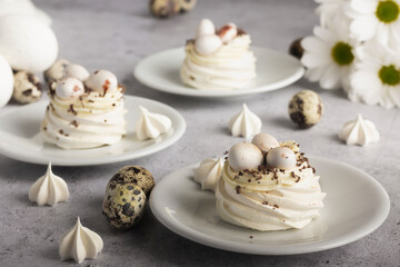 Meringue. Assorted meringue dishes with quail egg garnish, presented with white flowers and mottled gray background.