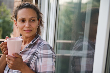 Attractive Hispanic middle-aged woman enjoying her morning coffee in the balcony