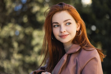 portrait of happy redhead woman in coat looking away.