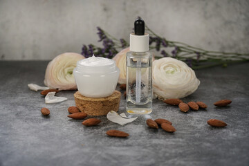  Almond water in glass dropper bottle for skin care and face cream on grey background with almonds...