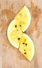 Sliced yelow watermelon isolated on a wooden plate, top view