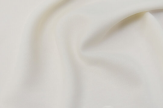 Close-up texture of natural beige or ivory fabric or cloth in brown color. Fabric texture of natural cotton or linen textile material. Beige canvas background.