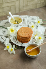 Obraz na płótnie Canvas Honey cookies with natural patterns on a plate on a dinner table with flowers and tea. Food photography in light colors with cookies and spring daffodils.