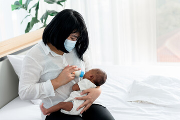 Portrait images of  Asian mother Sitting on bed, and feed milk from bottle milk to his 12-day-old baby newborn son, to family and food for infant concept.