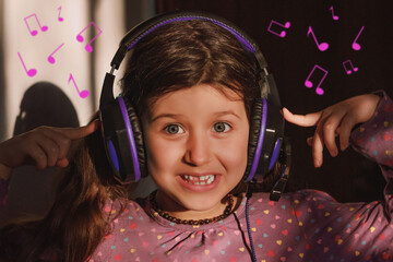 Portrait of a happy smiling girl child with dark hair in headphones listening to music indoors,...