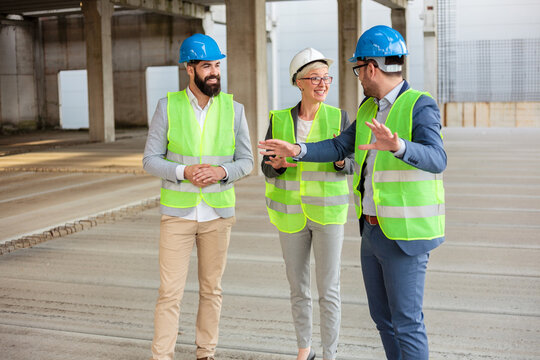 Team of successful young architects and business partners checking work progress on a construction site. Architecture and teamwork concept.