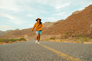 Cheerful young latin woman running, feeling free in the middle of a lonely road in the mountains of Baja California Sur. copy space.