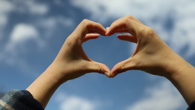 Girl hand heart shaped love blue sky