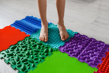 The child walks on an orthopedic foot massage mat. Prevention of flat feet