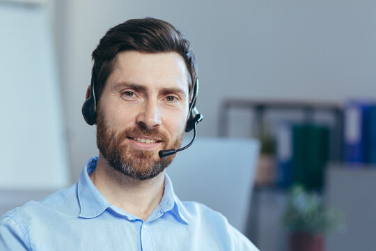 Close-up portrait of a businessman with a headset for a video call, a man looking at the camera smiling, a call center operator