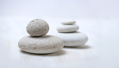 Fototapeta na wymiar grey pebble stones close up on abstract blurred light background. spa, relax, meditation concept. spiritual practice for harmony, life balance. minimal composition