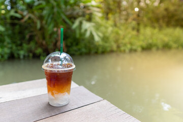 Fresh iced black coffee Arabica with sweet coconut juice for health care drinking on wooden table at cafe and nature environment with copy space in summer.