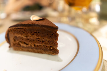 selected focus, Piece of chocolate cake on white plate in cafe. Delicious sweet cake on table on light background.