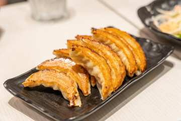 close up Japanese dumplings is called Gyoza or Jiaozi in China, gyoza with pork meat and vegetables on black plate, dumplings snack with soy sauce.