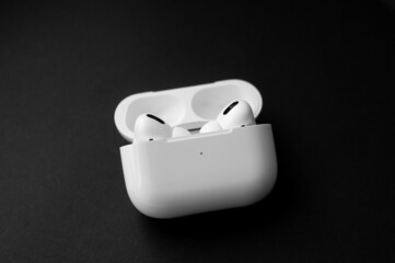 Top view white wireless headphones for smartphone vith charging case on black background. The concept of modern technology, gadgets.