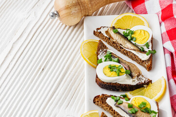 canapes with sprats on a white rustic wooden background