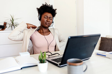 Young businesswoman experiencing a neck cramp during work. Overworked african woman with neck pain...