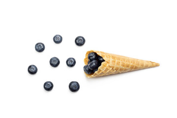 Fresh ripe blueberry in waffle cone. Ice cream cone with ripe sweet berries on white background with copy space. Summer creative concept, flat lay, Top view.