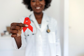 Female doctor with red ribbon. Cancer concept. Doctor Holds Red Ribbon to awareness world aids day Dec. 1. AID, HIV red ribbon. Symbol of awareness, charity, support in disease, illness.