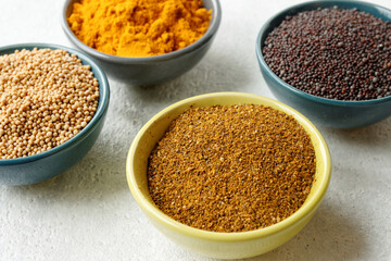 Powder spice blend from black and white mustard seeds and turmeric. Indian mustard powder seasoning in bowl.