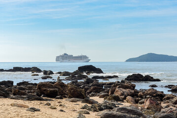 Fototapeta na wymiar Praia com rochas e cruzeiro ao fundo