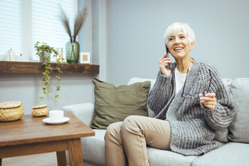 A smiling mature woman is talking on the phone. Mature woman in conversation using cellphone while laughing. A young cheerful lady is having fun during a fun conversation.