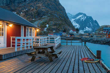 Landscape of red log cabins and snow capped mountains in Hamnoy Reine Moskenes Lofoten islands in...
