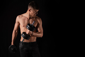 strong sexy man with dumbbells on a black background
