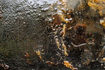 Texture, background, top view of a black tray smeared in fat, oil, pieces of old meat, after cooking. Photography, abstraction.