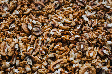 Background, texture of many brown walnuts, shelled nuts lying on the table. Food photography, top view, concept.