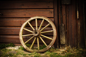 Fototapeta na wymiar Old rusty wagon wheel leans against barn.Peasant tool.