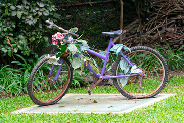 Fototapeta premium Old bicycle decorated with flowers in an outdoor garden, inspiration for social event, sunlight and relaxation space.