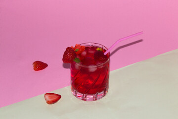 beautiful summer composition, cassa strawberry juice with strawberries and flowers in a glass and around the glass on a pastel pink green background