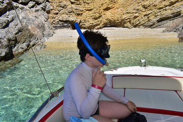 A boy in a mask for swimming on a boat in the sea