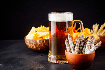 mug of beer and a set of dry fish snacks on a dark background