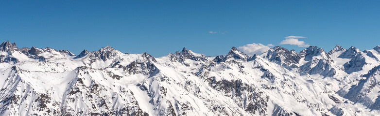 Panoramic view of winter snowy mountains in Caucasus region in Russia with blue sky