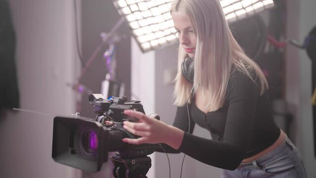 Confident cute woman filmmaker operate professional video camera on set 4K