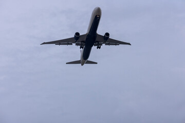 Jet plane seconds before landing on blue sky on a sunny day of aircraft silhouette seen from ground at international airport