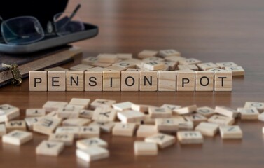 pension pot word or concept represented by wooden letter tiles on a wooden table with glasses and a book